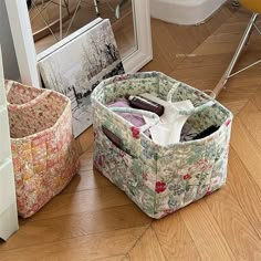 three storage baskets sitting on the floor next to each other in front of a mirror