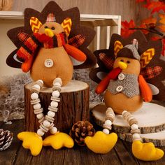 two stuffed turkeys sitting next to each other on a wooden table with pine cones