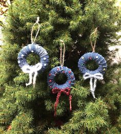 two wreaths are hanging from the branches of a tree, one is decorated with yarn