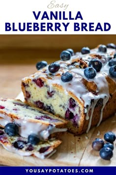 blueberry bread with white icing and fresh blueberries on top, sitting on a cutting board