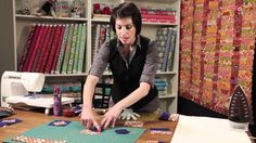 a woman is working on some crafting projects in her home studio, surrounded by quilts and sewing supplies