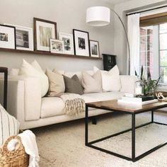 a living room filled with white furniture and pictures on the wall above it's windows