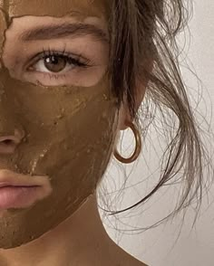 a woman with mud on her face looking at the camera while she is wearing a clay mask