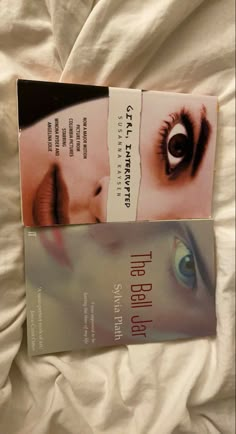 two books sitting on top of a bed next to each other in front of a white sheet