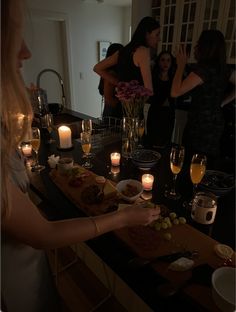 a group of people standing around a table with food and wine glasses on top of it