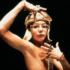 a man with no shirt wearing a gold headdress and holding his hands on his hips