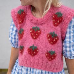 a woman with blonde hair wearing a pink knitted strawberry sweater and blue gingham dress