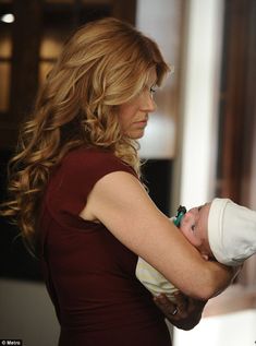 a woman holding a baby in her arms and looking at something on the wall behind her