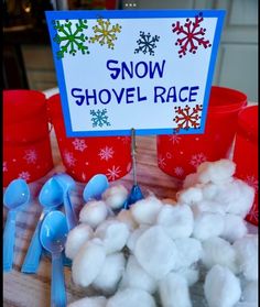 snow shovel race sign surrounded by plastic cups and spoons with cotton balls in them