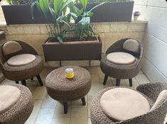 wicker chairs and foot stools are arranged on the floor in front of a potted plant