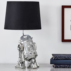 a lamp that is on top of a table next to some books and a star wars poster