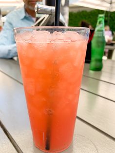 a drink sitting on top of a wooden table next to a man in a blue shirt