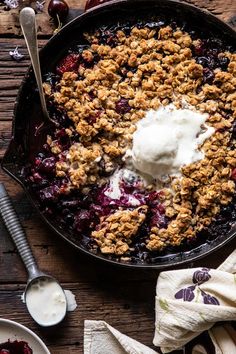 a skillet filled with crumbled fruit and ice cream on top of a wooden table