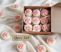 a box filled with pink frosted cupcakes on top of a white sheet