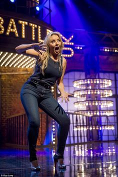 a woman is dancing on stage with lights behind her