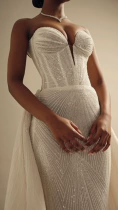 a woman in a wedding dress with her hands on her hip and wearing a necklace