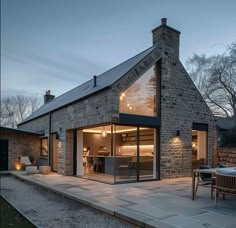 a brick house with an open patio and dining area in the back yard at dusk