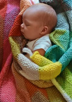 a baby wrapped in a blanket sleeping on top of a bed