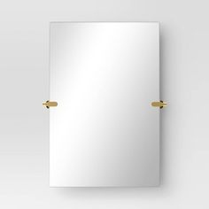 an empty mirror on the wall with gold handles