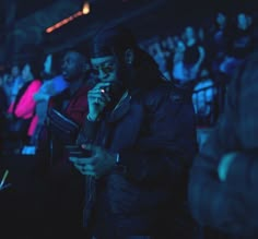 a man standing in front of a crowd holding a microphone and looking at his cell phone