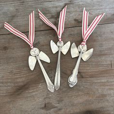 three silver spoons with red and white ribbons on them