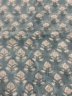 a blue and white leaf print fabric with small leaves in the center, on top of it