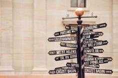 a pole with many different street signs on it in front of a building and an orange ball