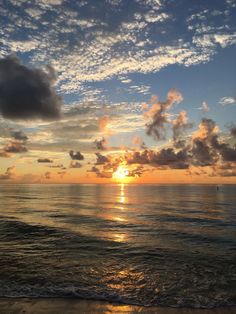 the sun is setting over the ocean with clouds in the sky and on the water