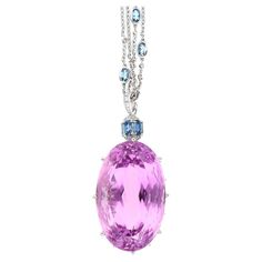 98.66 carat Kunzite and Aquamarine Pendant, an Art Deco masterpiece in 18K White Gold weighing 10.10 grams. This 21-inch pendant features an oval-cut Kunzite (36 x 22.2 MM) in a prong setting, emitting a captivating pink hue. Surrounding the Kunzite are eight Aquamarine stones (4.17CTTW, 7mm each), along with six more Aqua stones (1.09CTTW, 5 x 3 MM each). The ensemble is adorned with 37 round-cut Diamonds (0.36CTTW, 2mm - 1mm). Meticulously crafted, the pendant measures 4.75 cm, embodying moder Luxury Oval Jeweled Necklaces, Luxury Jeweled Oval Necklaces, Luxury Sapphire Pendant Necklace, Luxury Sapphire Necklace With Gemstone Accents, Luxury Platinum Oval Necklace, Luxury Oval Platinum Necklace, Luxury Oval Platinum Necklaces, Luxury Pendant Gemstones For Anniversary, Luxury Sapphire Gemstone Necklace