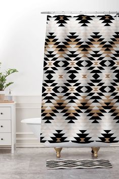 a black and white shower curtain with an abstract design in gold on the bottom half