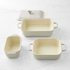 four white dishes with lids on a marble surface