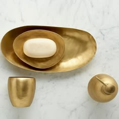 three brass dishes on a white marble countertop, one with an oval dish and the other with a rounded bowl