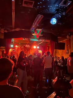 a group of people standing around in a room with red and green lights on the ceiling