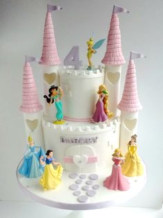 a birthday cake with princess figurines on top and castle in the back ground