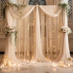 an elegant wedding ceremony with candles and drapes draped over the stage, decorated with white flowers and greenery