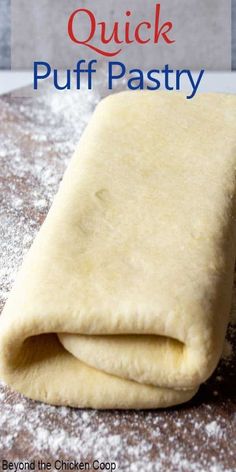 an uncooked puff pastry sitting on top of a wooden table next to powdered sugar