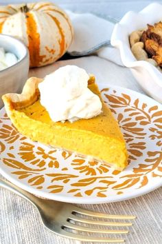 a slice of pumpkin pie on a plate with whipped cream and pecans in the background