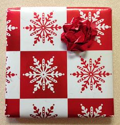 a present wrapped in red and white paper with snowflakes on the wrapping paper