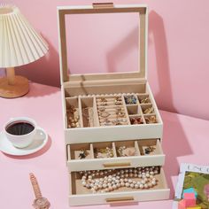 an open jewelry box sitting on top of a pink table