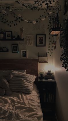 an unmade bed in a dimly lit room with pictures on the wall above it