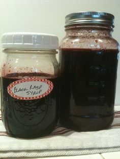 two jars filled with black liquid sitting on top of a white table cloth next to each other