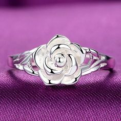 a white rose ring sitting on top of a purple cloth