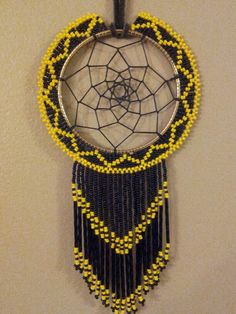 a black and yellow beaded dream catcher hanging on a wall