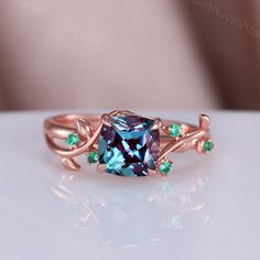 a fancy ring with blue and green stones on it's sides, sitting on a white surface