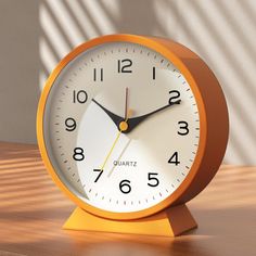 an orange clock sitting on top of a wooden table