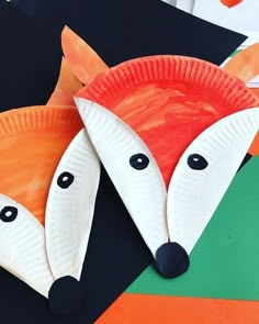 two paper plates shaped like foxes on top of each other, with eyes and noses