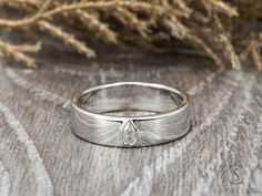 a close up of a wedding ring on top of a wooden table next to some branches