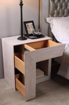 a night stand with two drawers and a lamp next to it on top of a bed