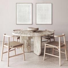 a dining table with chairs around it in front of two pictures on the wall above