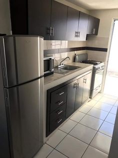 an empty kitchen with stainless steel appliances and tile flooring is pictured in this image